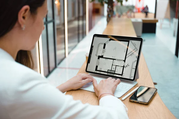 An architect or interior designer works remotely. A young freelance woman works with an engineering floor plan. Stock Picture