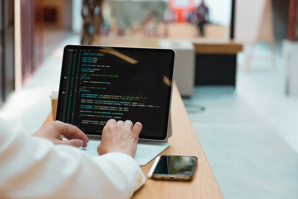 En frilansande programmerare arbetar på distans, en ung kvinna sitter vid ett bord i ett coworking eller business center — Stockfoto