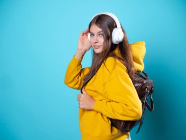 Sırt çantası ve kulaklığı olan, müzik dinleyen ya da konferans kaydeden genç bir öğrenci..