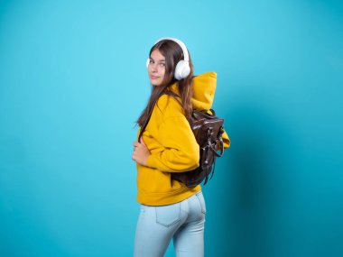 Sırt çantası ve kulaklığı olan, müzik dinleyen ya da konferans kaydeden genç bir öğrenci..