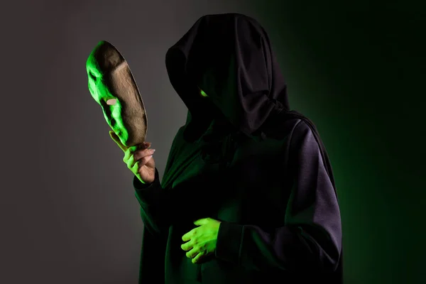 An anonymous villain, a hidden figure in a black cape with a hood. A mystical character Stock Image