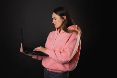 Elinde laptop olan bir öğrenci ya da serbest çalışan biri. Pembe kapüşonlu çekici bir kadın uzaktan çalışıyor.