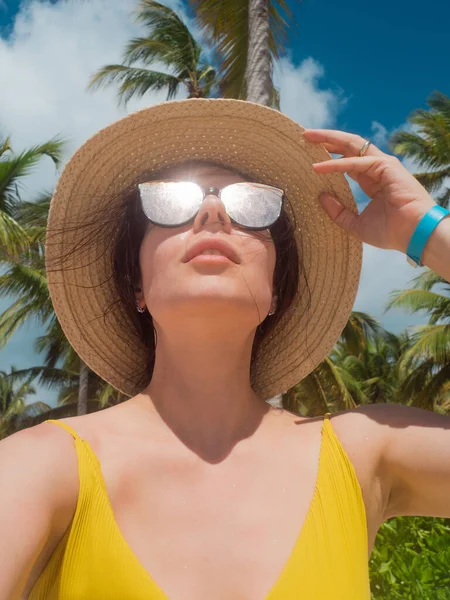 Une jeune femme en lunettes de soleil et un chapeau de paille sur une île tropicale. — Photo
