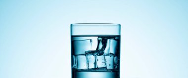 Mavi zemin üzerinde bir bardak su nükteli buz.