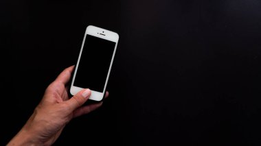 Kadın sol yakın plan, siyah arkaplanda yazı için siyah ekranlı bir telefon tutuyor.
