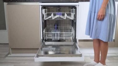 Kadınların elleri boş bir bulaşık makinesinin ön tarafındaki rafı kapatıyor. Yüksek kalite 4k görüntü