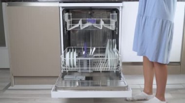 Bir ev hanımı kirli çatal ve kaşıkları bulaşık makinesinin ön tarafına yakın çekime koyar. Yüksek kalite 4k görüntü