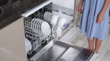 Bir kadının eli bulaşık makinesinin üst rafını kirli bulaşıklarla kapatır. Yüksek kalite 4k görüntü