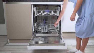 Ev hanımı kirli bulaşıkları bulaşık makinesinin önüne yakın plan 4K koyar.