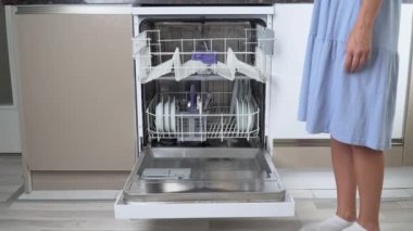 Bir kadının elleri bulaşık makinesinin üst rafına kirli bulaşıkları doldurur.