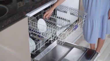 Bir kadının eli bulaşık makinesinin üst rafına kirli tabaklar ve kupalar koyar. Yüksek kalite 4k görüntü