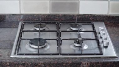 Ev hanımı gaz ocağında yemek pişiriyor, tavayı ocağın üstüne koyuyor.