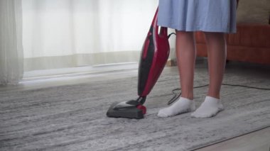 Ev hanımı halı süpürgesini temizliyor.