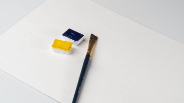 Çarşafta boya ve suluboya hendeklere mavi ve sarı renkler çizmek için bir fırça var. Yüksek kalite fotoğraf