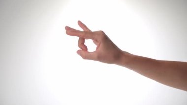 Beyaz arka planda bir kadın eli. El hareketi, alnına tıklamak, parmaklarınla küçük bir nesne fırlatmak. Yüksek kalite 4k görüntü