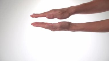 Kadın eli - avuç içi hareketi, beyaz arka plandaki avuç içleri arasındaki mesafeyi arttırır ve azaltır. Yüksek kalite 4k görüntü