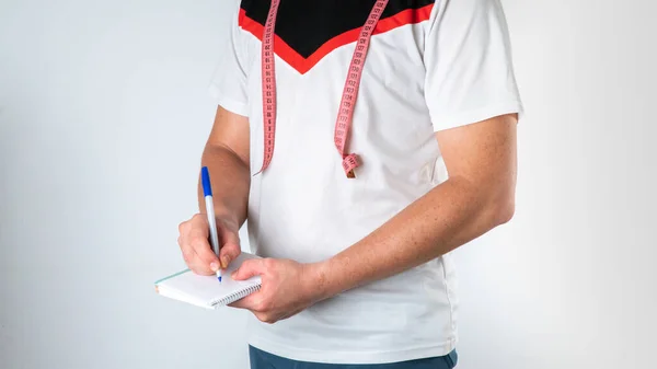 A man with a notebook and measuring tape, a trainer nutritionist makes up the diet and sports. High quality photo