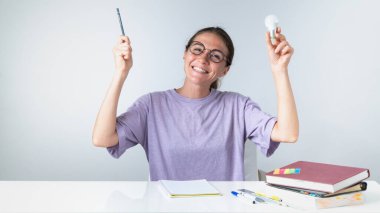 Bir kalem ve bir ampul ile neşeli bir öğrenci, bir fikir ya da cevap onun çalışmaları sırasında geldi. Yüksek kalite fotoğraf