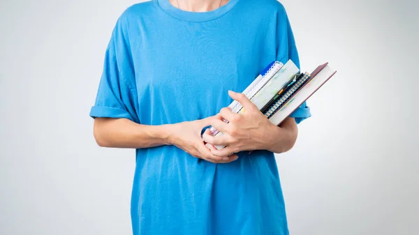 A student holds notebooks, books, a notebook, notebooks in her hands on a white background. High quality photo