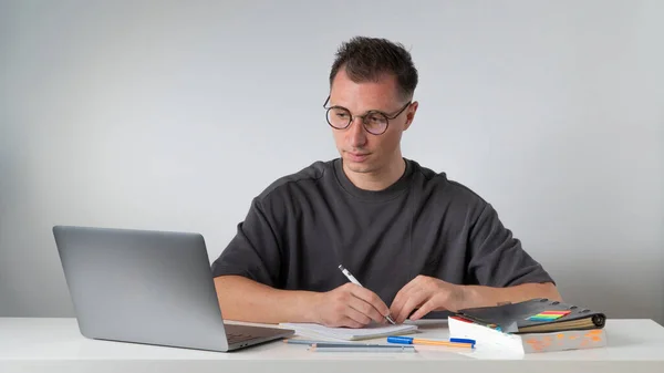 Een Man Aan Zijn Bureau Schrijft Een Notitieboekje Kijkt Naar — Stockfoto