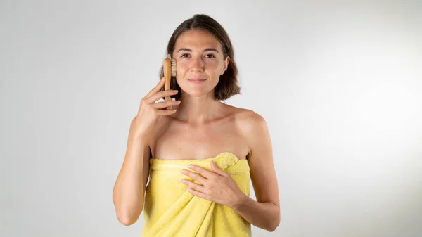 Duştan sonra bir kadın yüzüne fırçayla masaj yapar - evde kendine bakım. Yüksek kalite fotoğraf