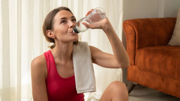 Woman drinks water after home workout, close-up. High quality photo