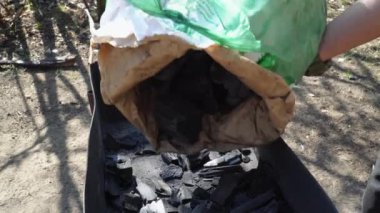 Ormanda barbekü ateşi yakmak için torbadan ızgaraya kömür dökülüyor. Yüksek kalite 4k görüntü