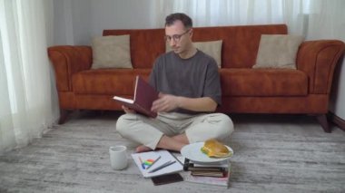 Aç öğrenci evde çalışırken, evde eğitim görürken büyük bir sandviç yiyor. Yüksek kalite 4k görüntü