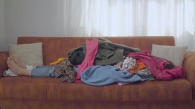 Bir kadın dağ gibi giysilerin altından çıkıyor. Bilinçli tüketim, çevresel bir eğilim. Yüksek kalite 4k görüntü