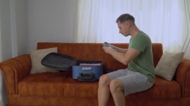 Bir adam iş seyahatinde bavulunu toplar, giysileri dikkatlice katlar ve el bagajına dizüstü bilgisayar koyar. Yüksek kalite 4k görüntü