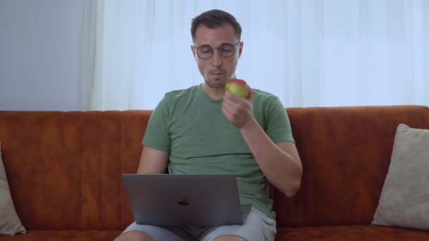 男はノートパソコンで働き リンゴを食べる 高品質4K映像 — ストック動画