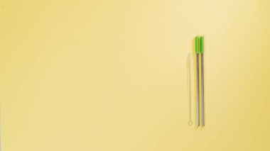 İçecekler için metal pipetler ve onları sarı arka planda temizlemek için fırça. Yüksek kalite fotoğraf