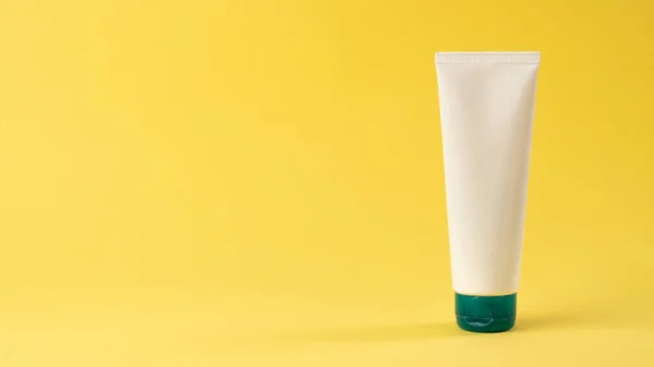 A tube of face or hand cream on a yellow background with space for label and text. High quality photo