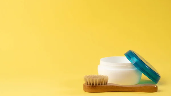 Sarı arka planda bir kavanoz krema ve masaj fırçası. Yüksek kalite fotoğraf