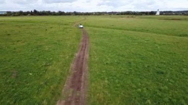 Yeşil bir tarlanın ortasında çamurlu bir yolda at arabası süren bir at, hava fotoğrafçılığı. Yüksek kaliteli FullHD görüntüler
