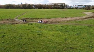 Atı olan bir araba, sonbaharda yeşil bir arazide yürüyen insanları sollar. Yüksek kaliteli FullHD görüntüler