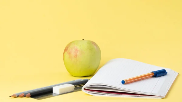 Workbook with pen and pencils for studying, apple for a snack. High quality photo