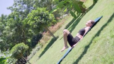 Kadınlar parkta yoga yapıyor, bacaklar kafanın arkasında kamera ile dönüyor. Yüksek kalite 4k görüntü