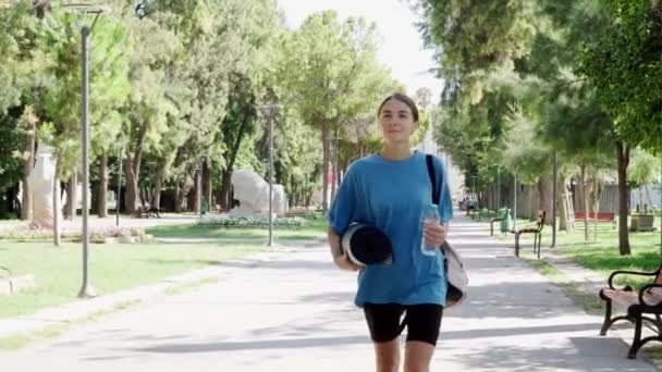 Una Mujer Lleva Una Esterilla Yoga Una Botella Agua Naturaleza — Vídeos de Stock