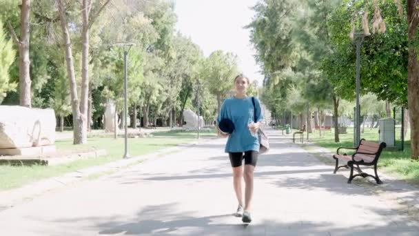 Μια Γυναίκα Χαλάκι Και Νερό Στο Χέρι Περπατάει Στο Πάρκο — Αρχείο Βίντεο