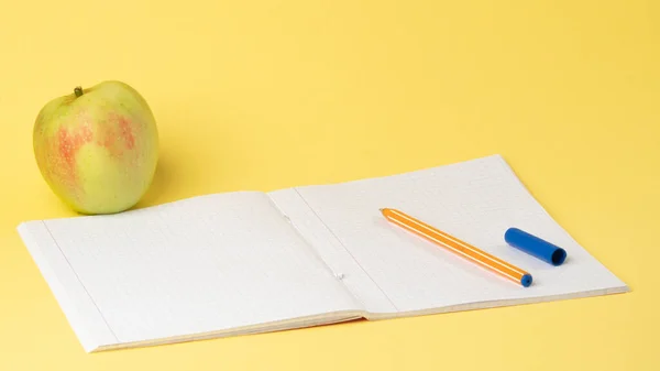 Sarı zemin üzerinde elma ve kalem olan kareli defteri aç, çalış. Yüksek kalite fotoğraf