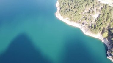 Ormanı ve mavi suyu olan kayalık bir sahil, İHA 'lı hava fotoğrafçılığı. Yüksek kaliteli FullHD görüntüler