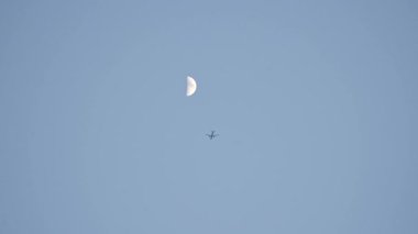 Uçak alacakaranlıkta ayın arka planına doğru uçar. Yüksek kalite 4k görüntü