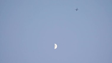 Uçak alacakaranlıkta ayın arka planına doğru uçar. Yüksek kalite 4k görüntü