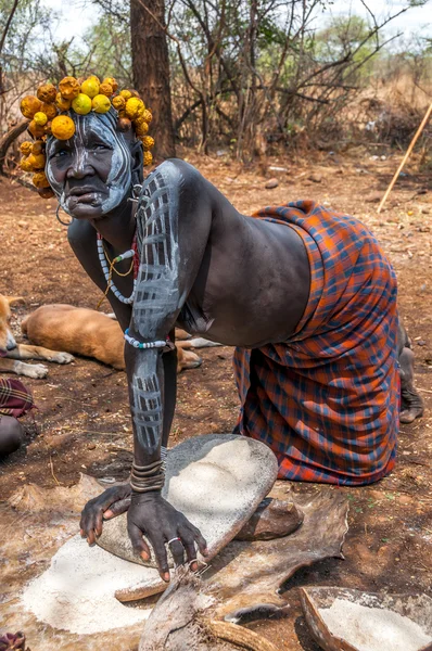 Omo valley people - mursi frau, die sorghum mahlt — Stockfoto