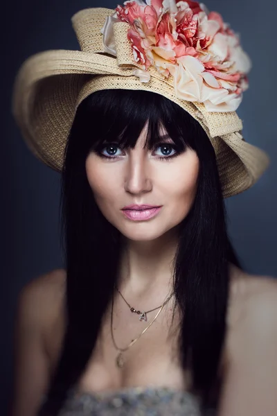 Porträt eines schönen brünetten Mädchens mit Strohhut und Blütenkopf im Studio — Stockfoto