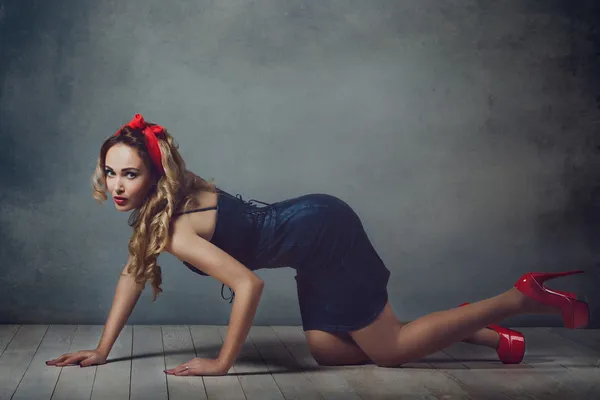 Sexy mujer rubia en jeans vestido de sol y zapatos rojos pin up girl mujer retro piernas sexy y un capitium rojo en su cabeza arrastrándose en el suelo sentado en el suelo y endereza el cabello — Foto de Stock