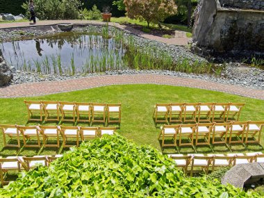 Açık hava seremonisi, çimenlikteki sandalyeli düğün resepsiyonu için hazırlanıyor.