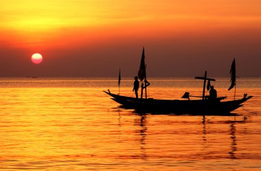 Silhouette of fisherman and boat under sunrise clipart