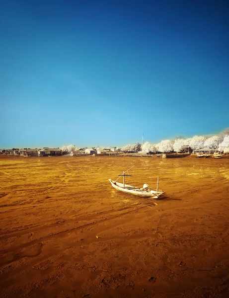 Разрушенная лодка на отступающем берегу — стоковое фото